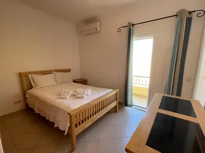 a bedroom with a bed and a large window at Moradia da Encosta- Vilamoura in Vilamoura