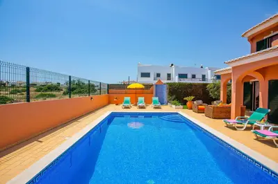 a swimming pool with chairs and a house at Villa Bali by Villa Plus in Albufeira