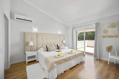a white bedroom with a large bed and a window at Villa Citrinos by Villa Plus in Almancil