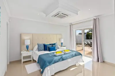 a white bedroom with a bed with blue pillows at Villa Pianda by Villa Plus in Almancil