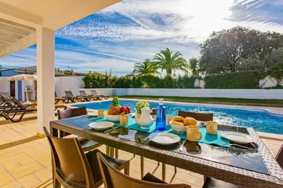 a table with food on it on a patio with a pool at Villa Pianda by Villa Plus in Almancil