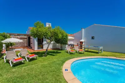 a yard with a pool and chairs and a house at Villa Sueste by Villa Plus in Albufeira