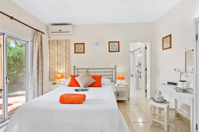 a white bedroom with a large bed with orange pillows at Villa Uma by Villa Plus in Loulé