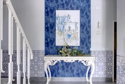 a staircase with blue walls and a white console with flowers on it at Palacete da Baixa by MY CHOICE in Faro