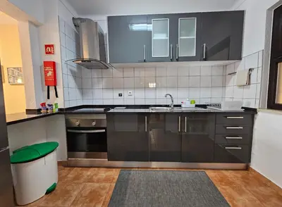 a kitchen with black cabinets and a sink and a trash can at T1 Poente da Aldeia 336 Albufeira in Albufeira