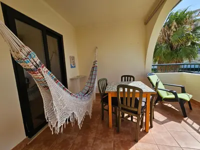 a dining room with a table and chairs and a hammock at T1 Poente da Aldeia 336 Albufeira in Albufeira