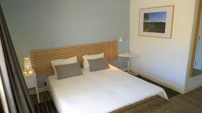 a small bedroom with a white bed with two pillows at Grey Heron Apartment in Quinta do Lago