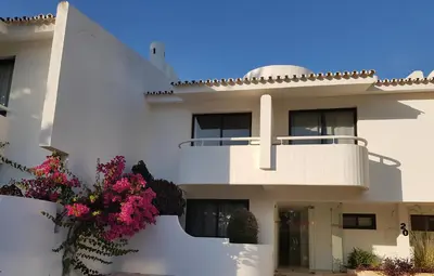 a white house with flowers in front of it at Grey Heron Apartment in Quinta do Lago