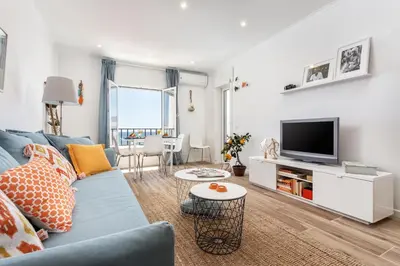 a living room with a blue couch and a tv at Modern ocean view apt 2 min walk to beach in Quarteira
