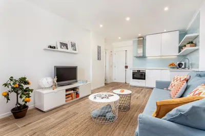 a living room with a blue couch and a kitchen at Modern ocean view apt 2 min walk to beach in Quarteira