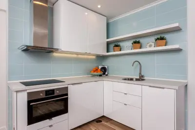 a kitchen with white cabinets and blue tiles at Modern ocean view apt 2 min walk to beach in Quarteira