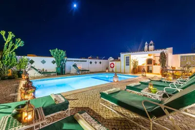 a swimming pool with green lounge chairs next to a building at Villa Galé Sun - Luxury, 5bed with free wifi, AC, private pool, 5 min from the beach in Guia