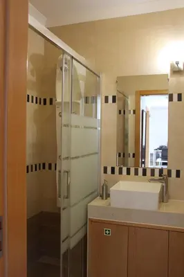 a bathroom with a sink and a glass shower at Ocean and pool in Olhos de Água
