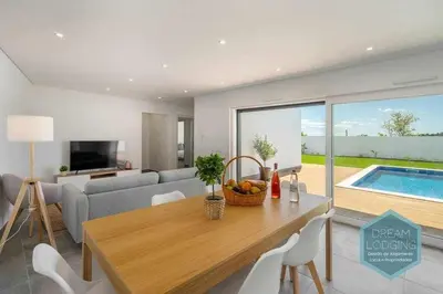 a living room with a dining table and a pool at Casa do Alto - Dream Lodging in Albufeira