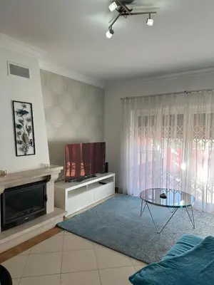 a living room with a tv and a glass table at V3 Vitória Boulevard in Vilamoura
