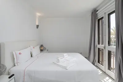 a white bedroom with a large bed and a window at Vilamoura Garden House with Pool & Parking, by Hopstays in Quarteira
