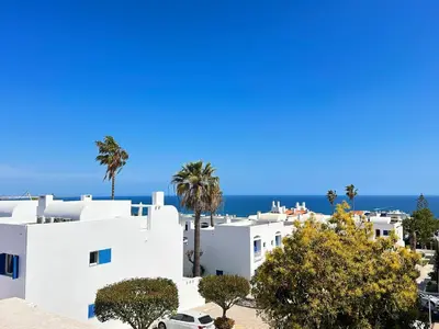 a dining room with a wooden table and white chairs at Sea & Sun WindMill Apartment by Be Cherish in Albufeira