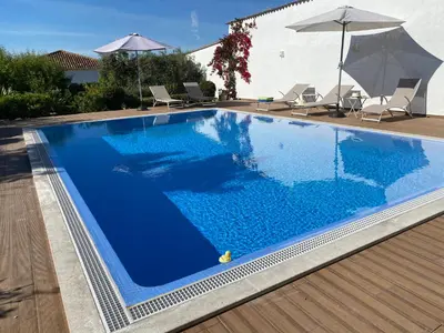 a large blue swimming pool with chairs and umbrellas at Casa Bravo in Querença