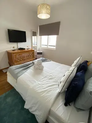 a large white bed in a room with a television at Neptuno IV - Vilamoura in Quarteira