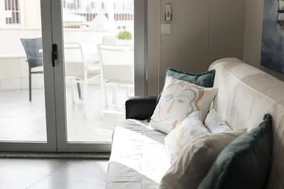 a white couch with a pillow with a face on it at Marina Luxor - Vilamoura in Quarteira