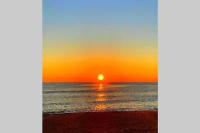 a sunset on the beach with the sun setting at Comfort Zone beach apartment in Quarteira