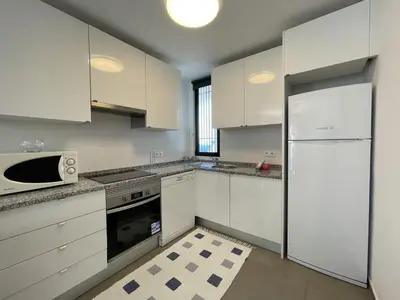 a kitchen with white cabinets and a white refrigerator at Vila Flor - Vilamoura in Vilamoura
