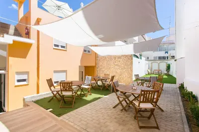 a patio with tables and chairs and a building at Casa Amarela Guesthouse in Albufeira