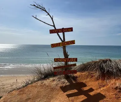 a sign on a beach with the ocean in the background at Falesia Beach Town house 2 bedroom in Olhos de Água