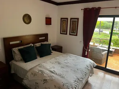 a bedroom with a bed with green pillows and a window at Falesia Beach Town house 2 bedroom in Olhos de Água