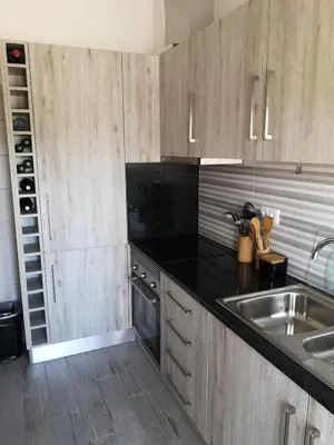 a kitchen with wooden cabinets and a stainless steel sink at Apartamento Recanto do Avô in Albufeira