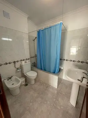 a bathroom with a toilet sink and a blue shower curtain at studio para 2 pessoas in Albufeira