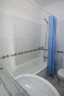a bathroom with a tub and a toilet and a blue shower curtain at studio para 2 pessoas in Albufeira