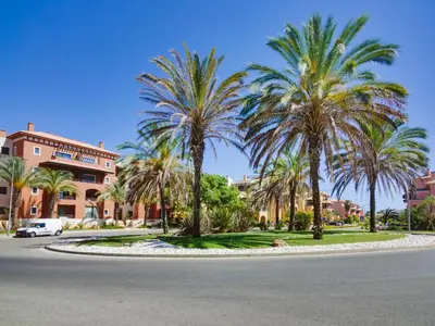 a street with palm trees in front of a building at AL - Victoria Gardens in Vilamoura