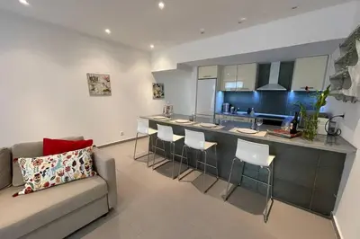 a living room with a couch and a kitchen at Janelas Verdes 37 in Faro