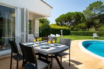 a dining table and chairs next to a swimming pool at Villa Macuti by SAPvillas in Vilamoura