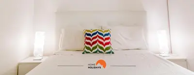 a white bed with a colorful pillow on it at #057 T1 Rossio 43D by Home Holidays in Albufeira