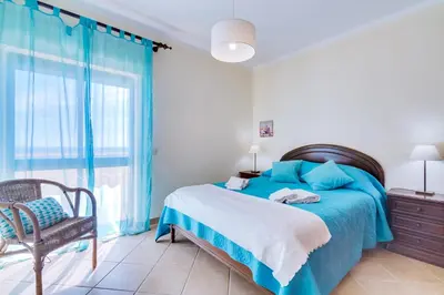 a bedroom with a blue bed and a chair at InfiniteSeaView - Quarteira at Homesbyfc in Quarteira