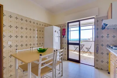 a kitchen with a table and a refrigerator at InfiniteSeaView - Quarteira at Homesbyfc in Quarteira