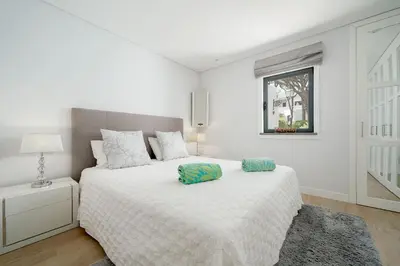 a white bedroom with a bed and a window at Casa Alessa - Vale de Lobo in Almancil