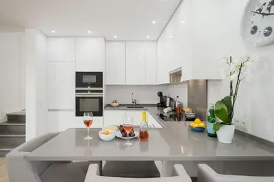 a white kitchen with a table and two glasses of wine at Casa Alessa - Vale de Lobo in Almancil