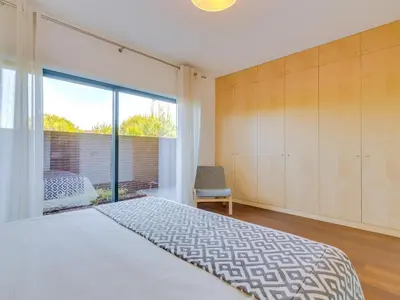 a bedroom with a bed and a large window at L'orangerie modern 1bdr apartment, ground floor in Vilamoura