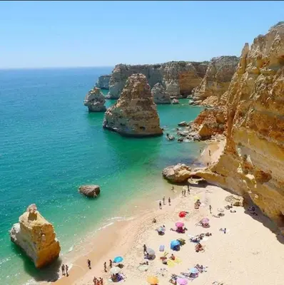 a group of people on a beach near the ocean at Appartement T1 Albufeira Strip Oura in Albufeira