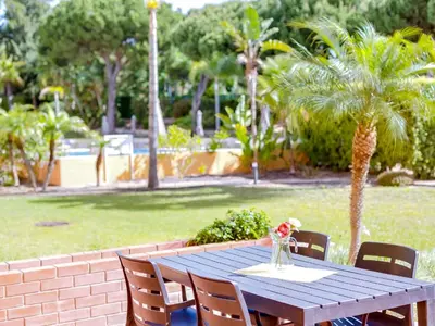 a wooden table with chairs and a vase of flowers at AL - Apartamento Vila Sol F5 L in Vilamoura