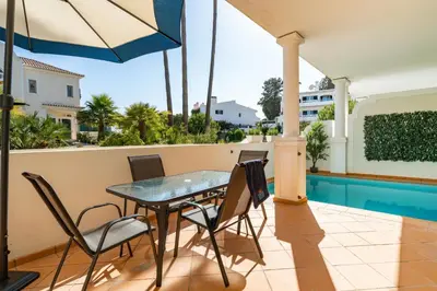 a patio with a table and chairs and a swimming pool at Vale de Lobo by Intiholidays in Vale do Lobo