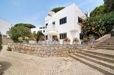 a white house with plants on a stone wall at Casa Harlequin in Vale do Lobo