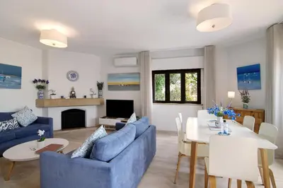 a living room with a blue couch and a table at Casa Harlequin in Vale do Lobo