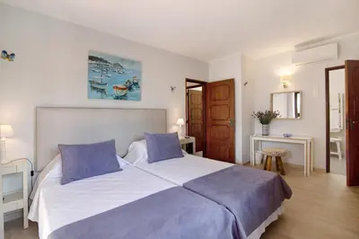 a bedroom with a large bed with blue pillows at Casa Harlequin in Vale do Lobo