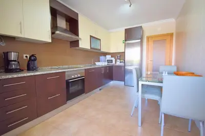 a kitchen with brown cabinets and a table with chairs at Perfect New Apartment in Albufeira in Albufeira