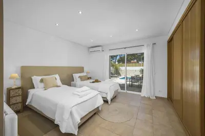 a bedroom with two beds and a large window at Villa Falesia Blue by Villa Plus in Olhos de Água