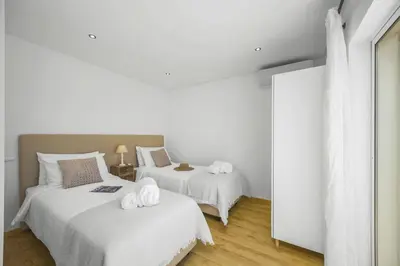 two beds in a room with white walls and wood floors at Villa Falesia Blue by Villa Plus in Olhos de Água